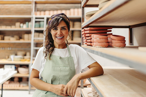 Female potter smiling at the camera in her shop