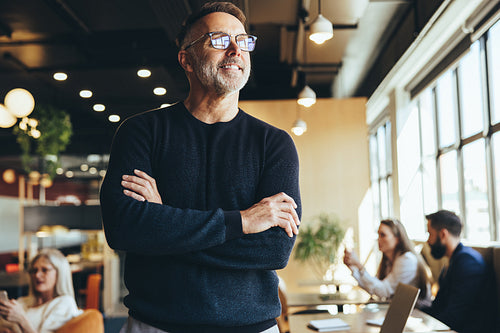 Contemplative businessman standing in a co-working space
