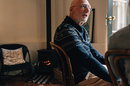 Senior man sitting on a chair at home and talking