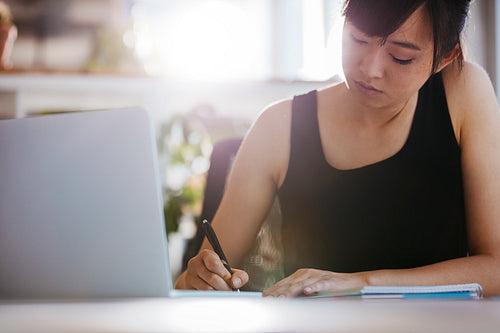 Young woman working at her desk taking notes