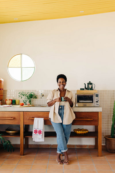 Mature Brazilian woman smiling and holding a cup of coffee in the kitchen