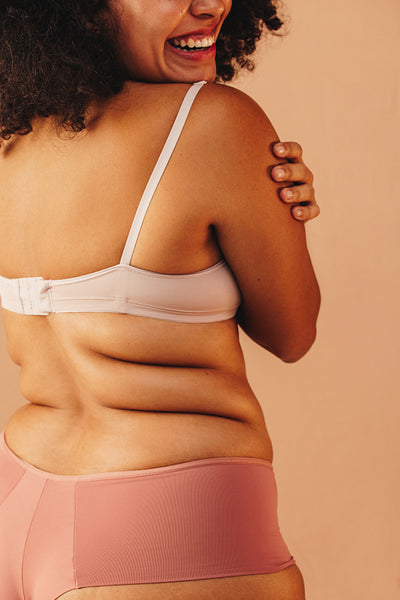 Happy plus size woman embracing her body in a studio