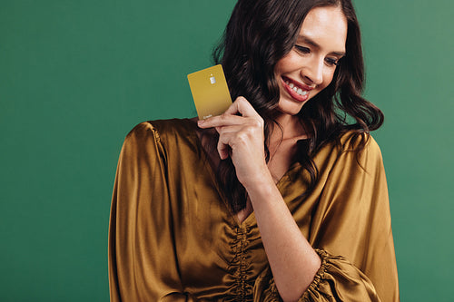 Enjoying a healthy credit score: Female customer holds up her gold bank card in a studio