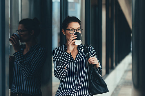 Businesswoman outside office building drinking coffee
