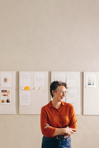 Mature designer looking away with a happy smile in her office