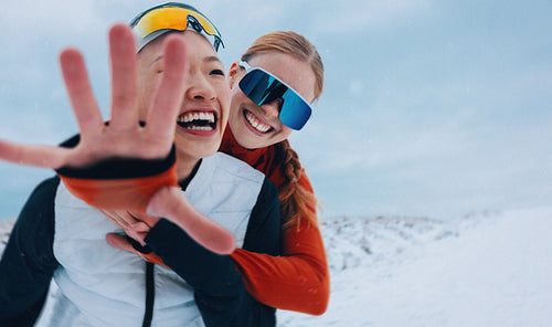 Women running together in winter snow during playful fitness training