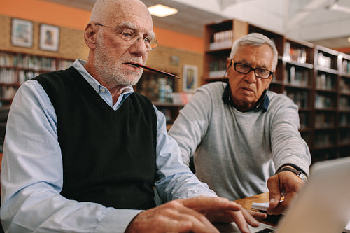 Senior men sitting in a classroom working on laptop