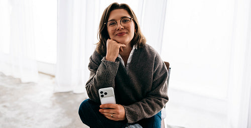Professional woman portrait with phone in bright indoor setting