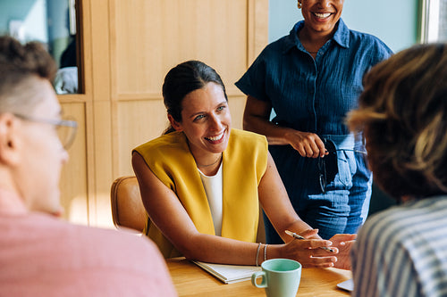 Smiling woman discussing ideas with colleagues around a table