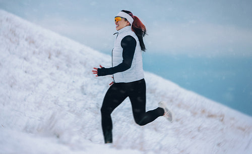 Woman sprinting uphill through snow in winter exercise training