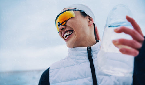 Joyful woman hydrating during snowy winter running session
