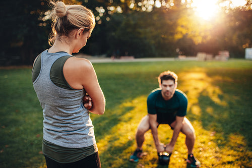 Female trainer in the park with man working out