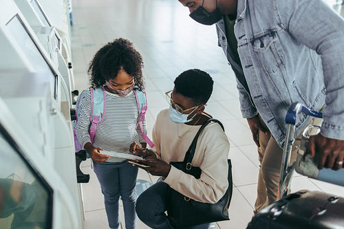 African family at airport looking boarding pass