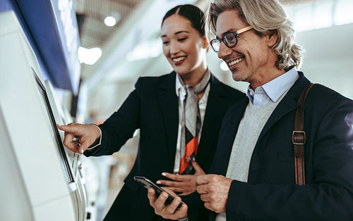 Flight attendant helping businessman with self check in