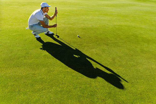 Male golfer check line for putting golf ball