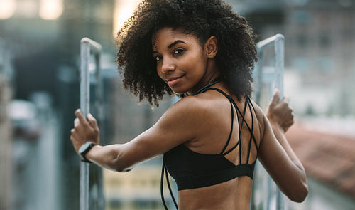 Smiling fitness woman standing on rooftop
