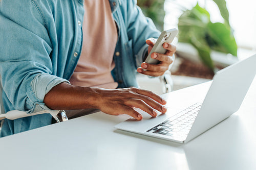 Young businessman using smartphone and laptop at the office