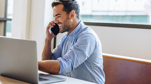 Happy freelancer calling client on cell phone