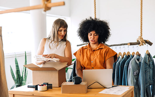 Clothing store owners preparing clothing parcels for shipping