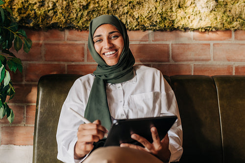 Happy Muslim graphic designer working in a cafe
