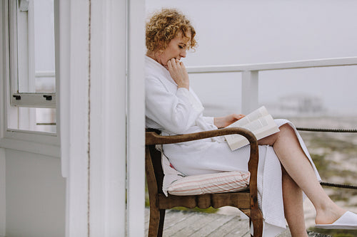 Woman reading a book sitting in balcony