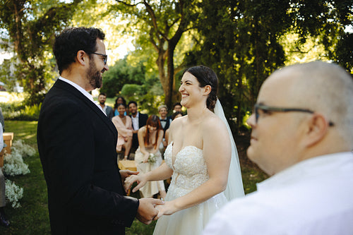 Outdoor wedding ceremony between a happy couple surrounded by loved ones