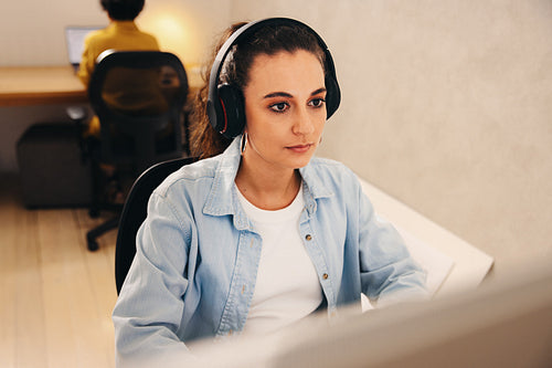Focused businesswoman wearing headphones working at her desk in a modern office