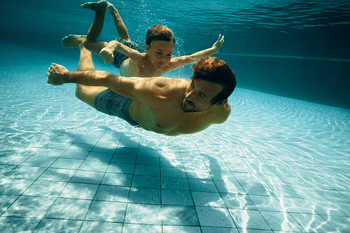 Father and young boy enjoying a playful underwater swim