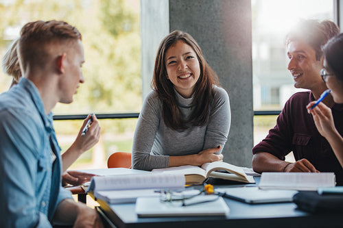 Smiling young woman with classmates in library