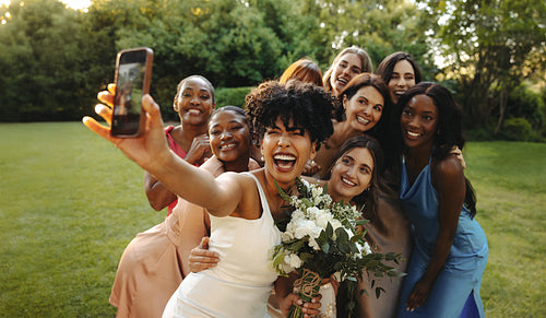 Bride and bridesmaids taking a celebratory selfie outdoors