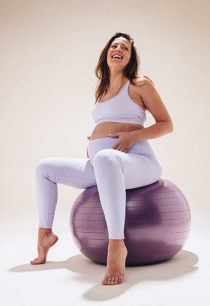 Pregnant woman smiling and exercising on yoga ball for antenatal fitness and wellbeing