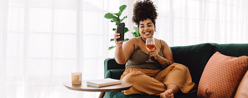Woman having wine and video call frineds using cell phone