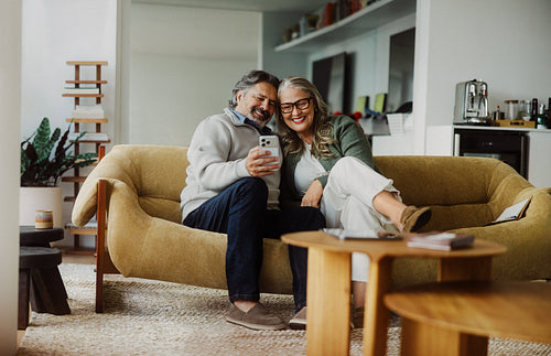 Seated senior shares a phone with a partner at home