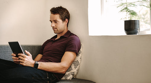 Freelancer looking at digital tablet sitting at home