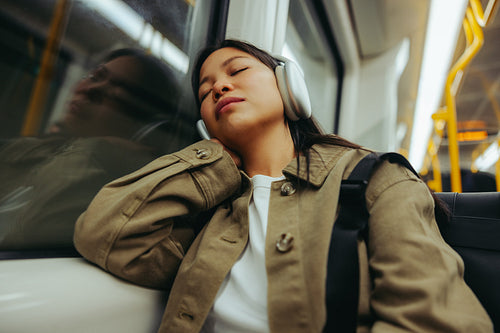 Commuter sleeping with headphones on during a train ride