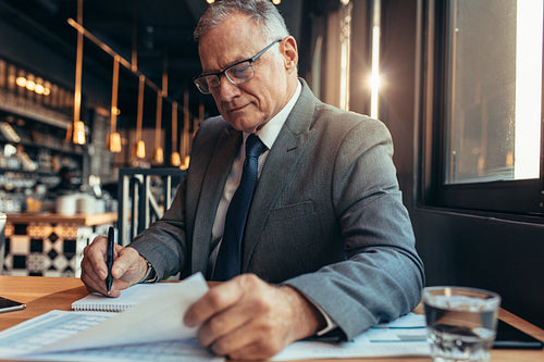 Senior businessman sitting at cafe and working