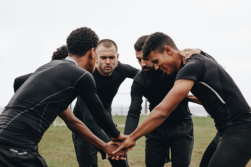 Football players in a huddle holding hands