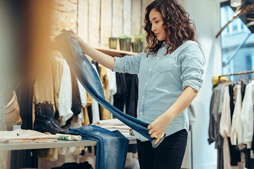 Woman checking quality of jeans in clothing store
