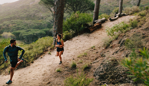 Couple of fit athletes running on mountain path