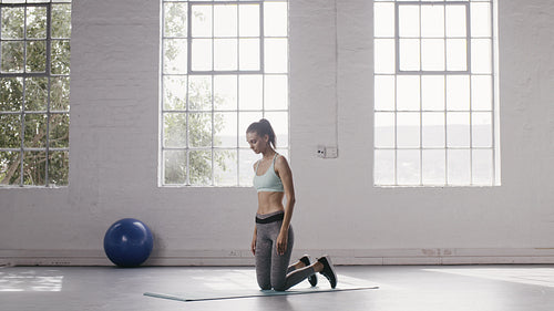 Woman doing one-legged down dog pose in yoga studio
