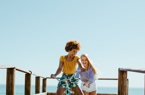 Friends playing with a bicycle on boardwalk