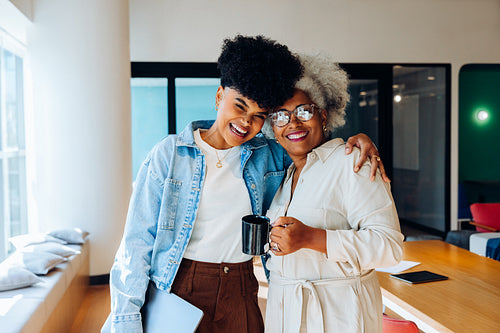 Work friends: Young Black woman and senior woman share a light moment