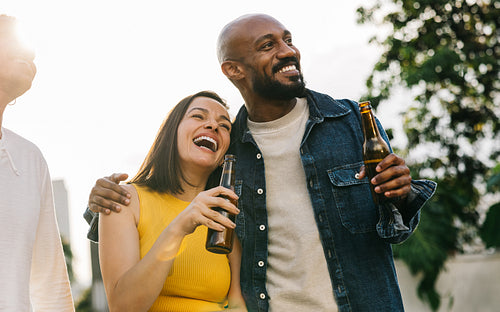 Happy friends hugging and enjoying drinks outside with warmth and affection