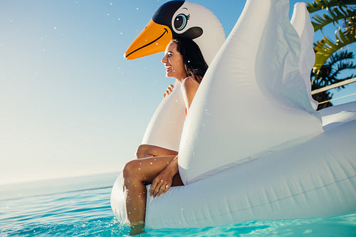 Woman having fun on floating toy in pool