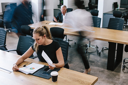 Businesswoman reviewing statistical reports in office