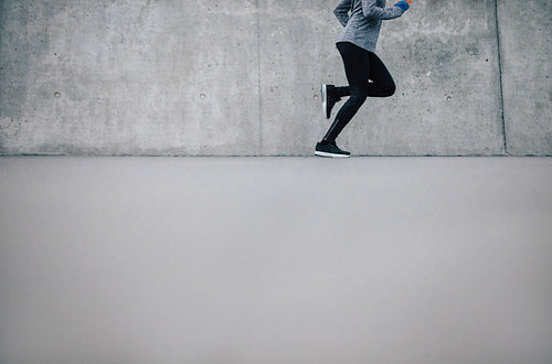 Female runner running on gray background