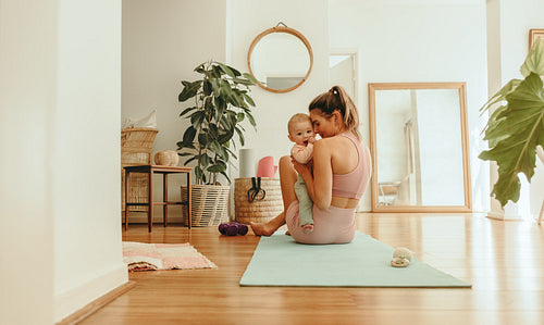 Affectionate mom working out with her baby at home