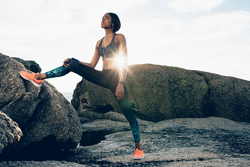 Fitness african woman standing by rock