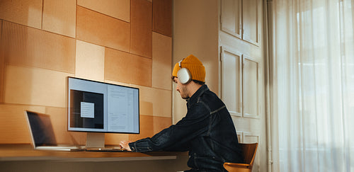 Focused man wearing headphones working at desk in office space