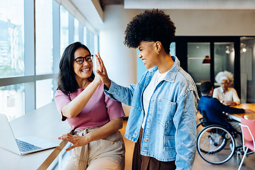 Two friends high five in a modern office